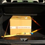 Zurrgurt sichert Kartonage im Kofferraum eines PKWs zur Ladungssicherung