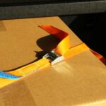 Spanngurt mit Klemmschloss sichert Kartonage im Kofferraum eines PKWs zur Ladungssicherung