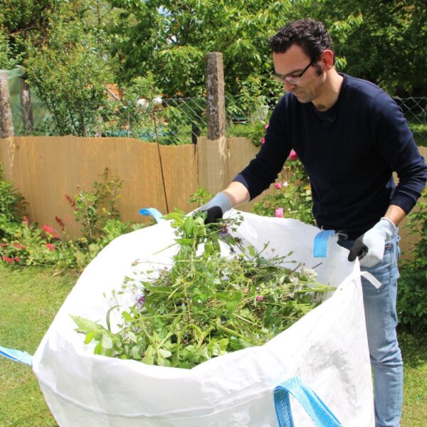 Person füllt den Big Buddy Gartensack mit Gartenabfällen und Gras.